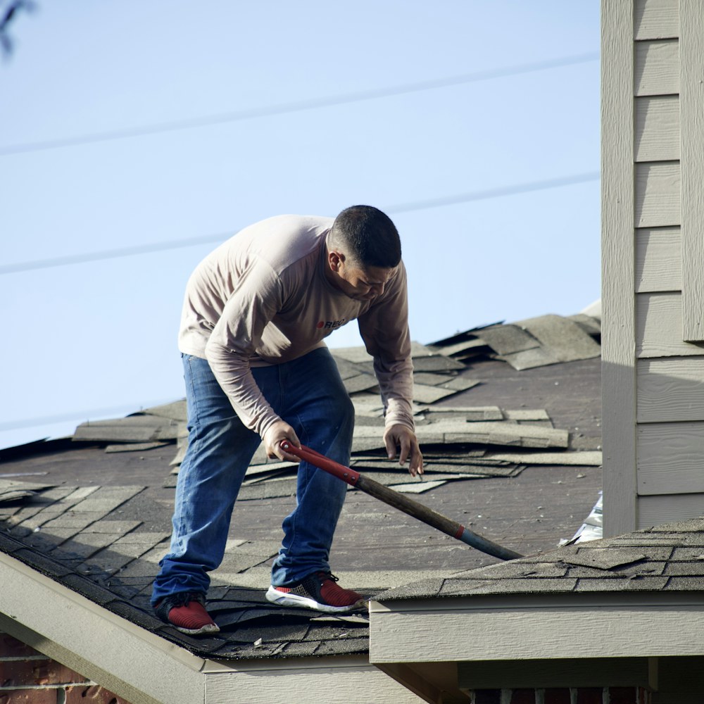 Roofer removing worn shingles during a roof repair
