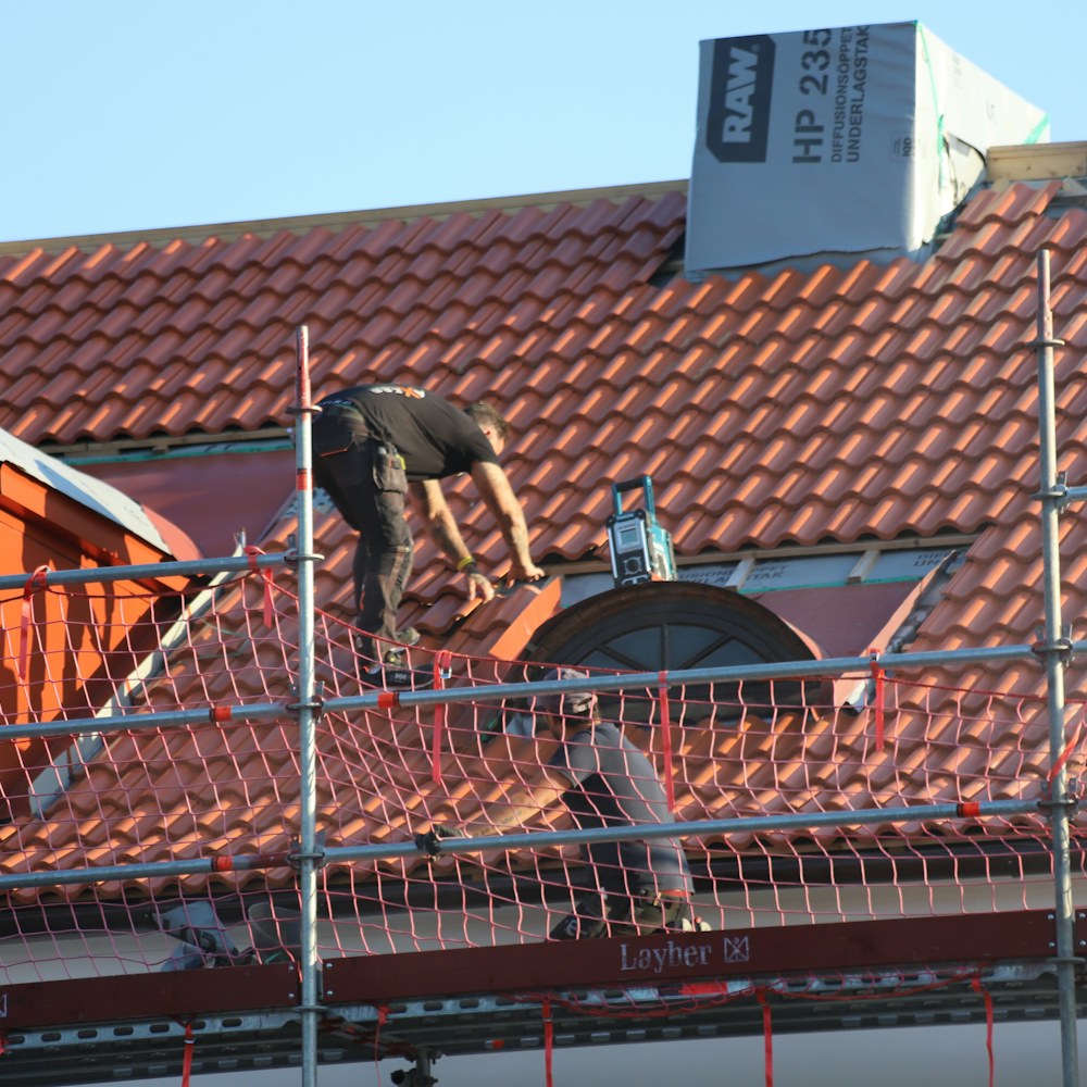 Craftsperson installing red tile roofing